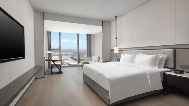 Una habitación de hotel moderna con una cama grande, un escritorio y un televisor.