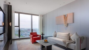 Una sala moderna con un sofá, un sillón rojo y una mesa de centro con fruta.