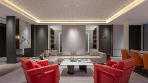 Una sala de estar moderna con un sofá color beige, sillones rojos y una mesa de centro de mármol.