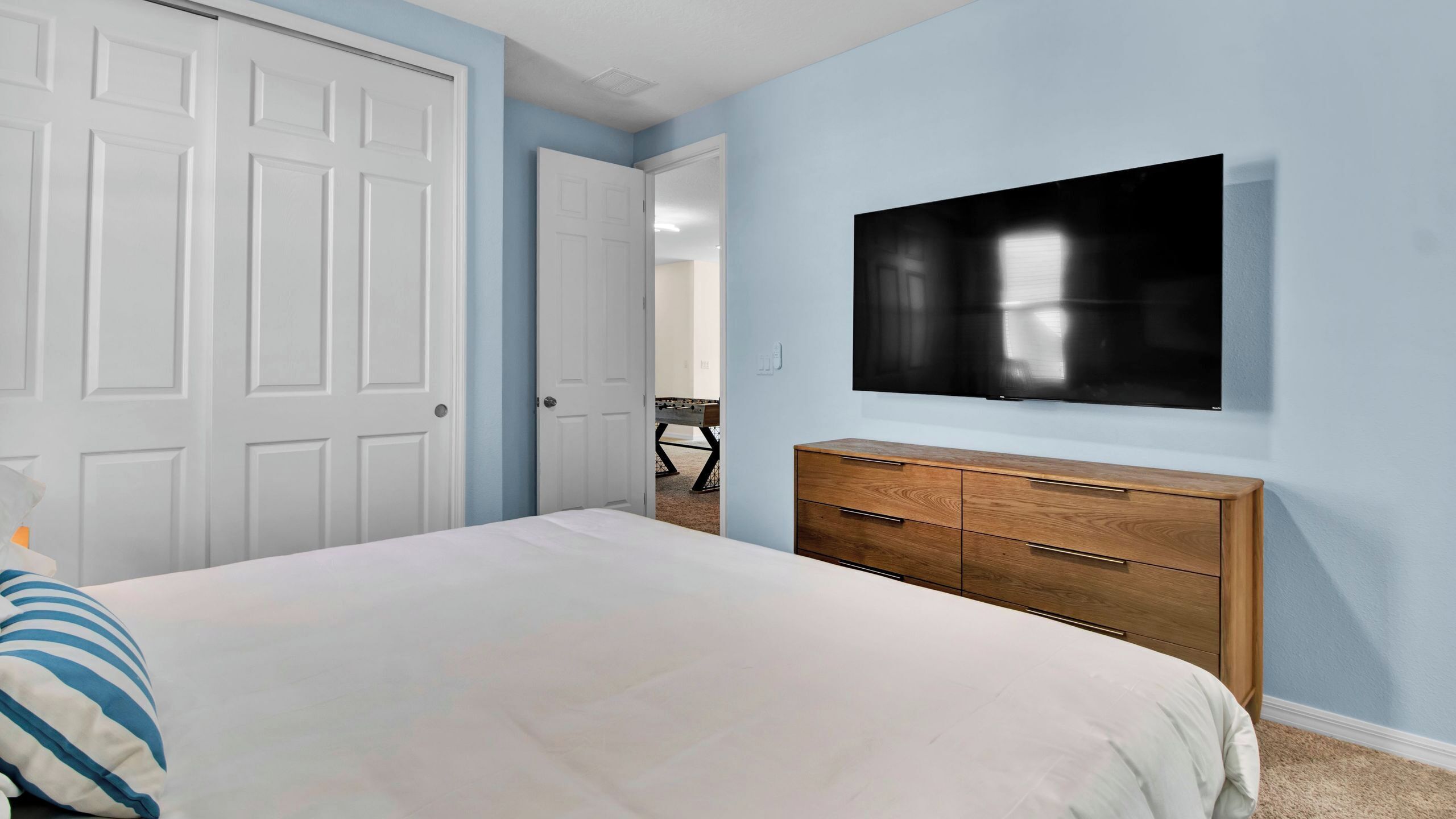 A bedroom with a bed, a dresser, and a TV mounted on the wall.