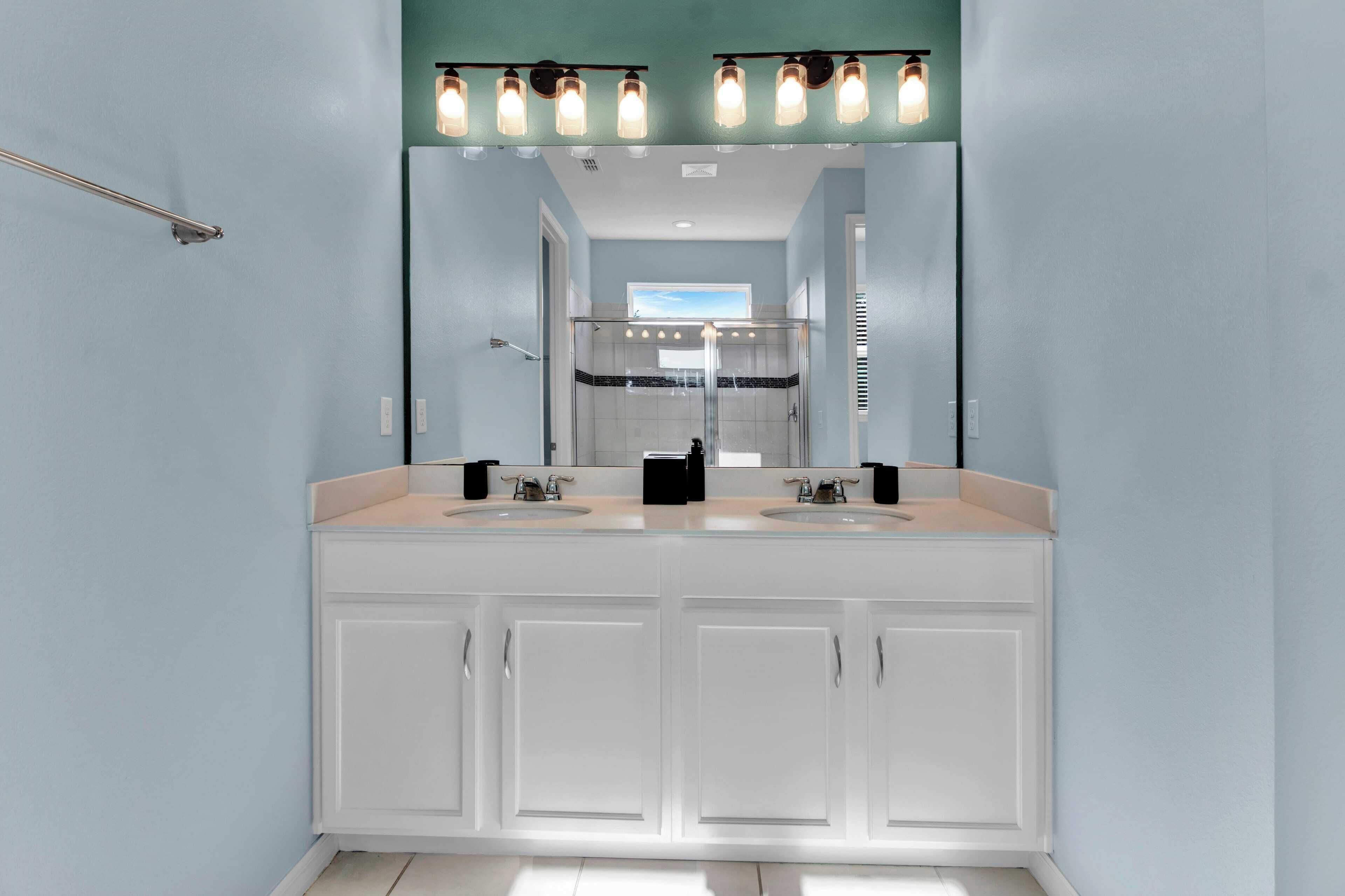 A bathroom with two sinks, a large mirror, and a shower area.