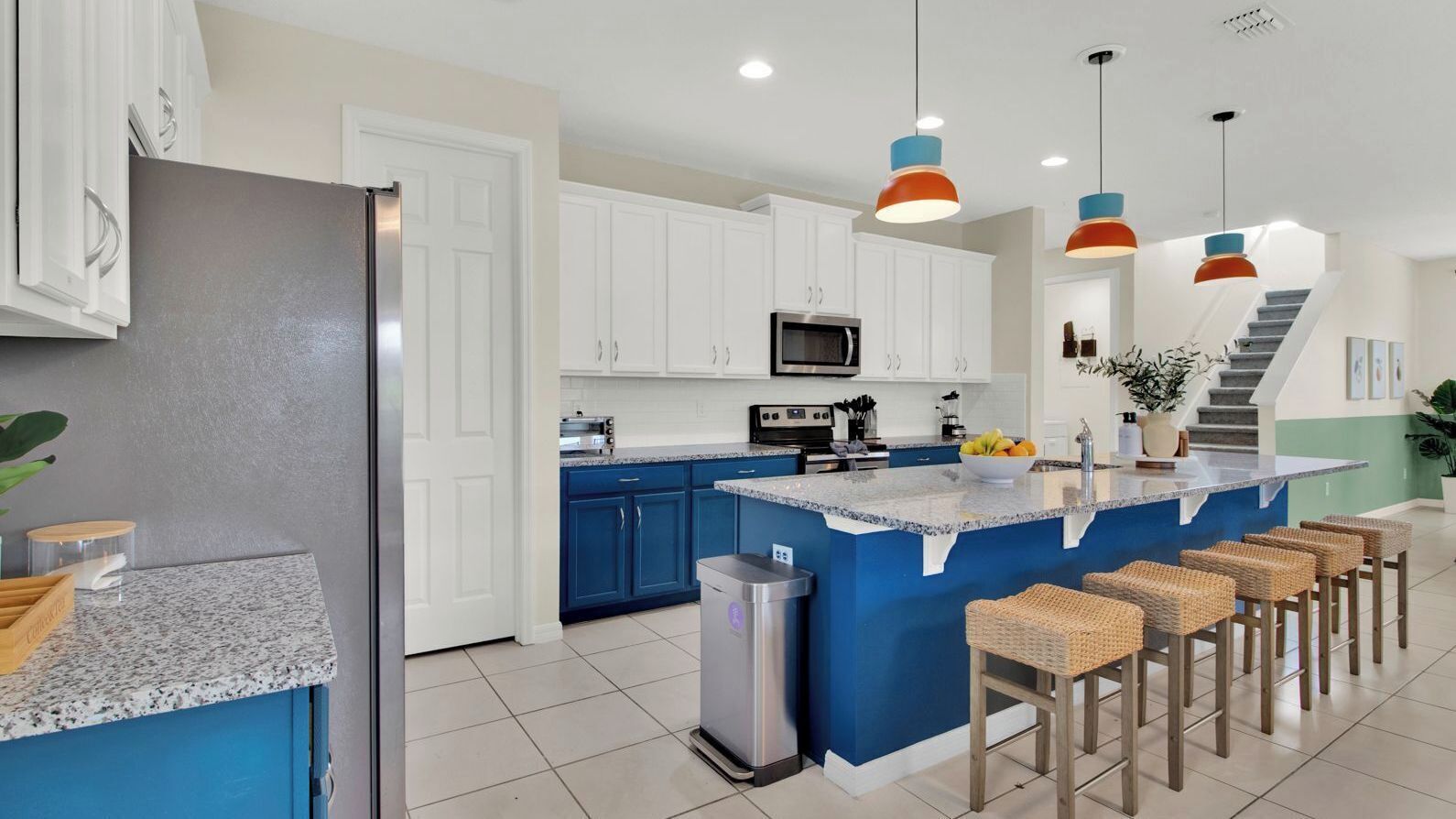 A modern kitchen with white cabinets, a blue island, and a stainless steel refrigerator.