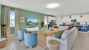 A modern living room with a sofa, two armchairs, a coffee table, and a TV. - Sleeps 20! 9bdr, Star Wars-themed Game Room, Pool, Hot Tub Nassau by Avantstay (Kissimmee)