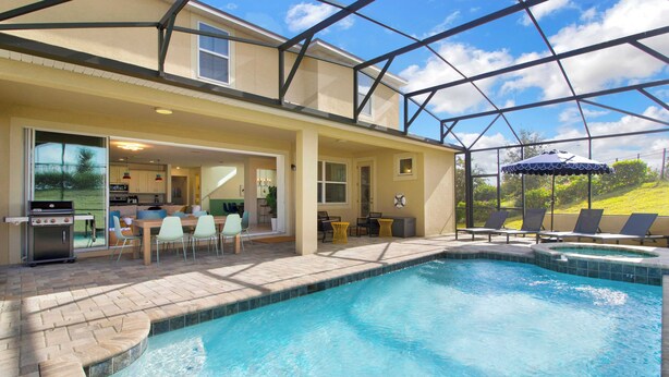 A swimming pool with a covered patio area, outdoor seating, and a view of the backyard. - Sleeps 20! 9bdr, Star Wars-themed Game Room, Pool, Hot Tub Nassau by Avantstay (Kissimmee)