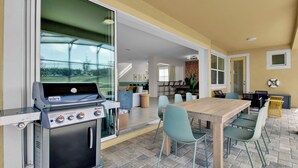 An outdoor patio with a Weber Spirit grill, a dining table with chairs, and a view of the backyard. - Sleeps 20! 9bdr, Star Wars-themed Game Room, Pool, Hot Tub Nassau by Avantstay (Kissimmee)
