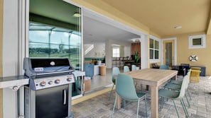 An outdoor patio with a Weber Spirit grill, a dining table with chairs, and a view of the backyard.