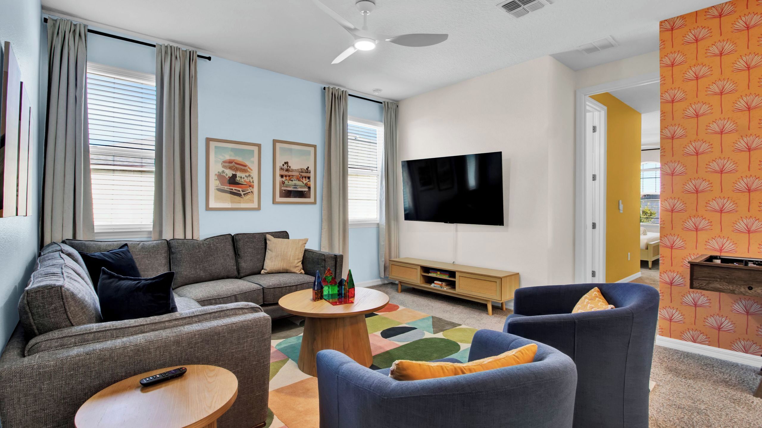 A living room with a sofa, chairs, a coffee table, a TV, and a bookshelf.