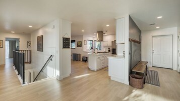 Una cocina amplia con una isla central, una zona de comedor con banco y una escalera que sube a otro nivel.