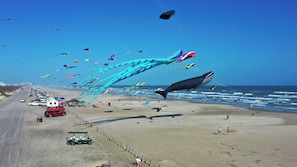 Une plage bordĂ©e dâune rangĂ©e de vĂ©hicules garĂ©s et, Ă gauche, un vĂ©hicule de type voiturette de golf.
