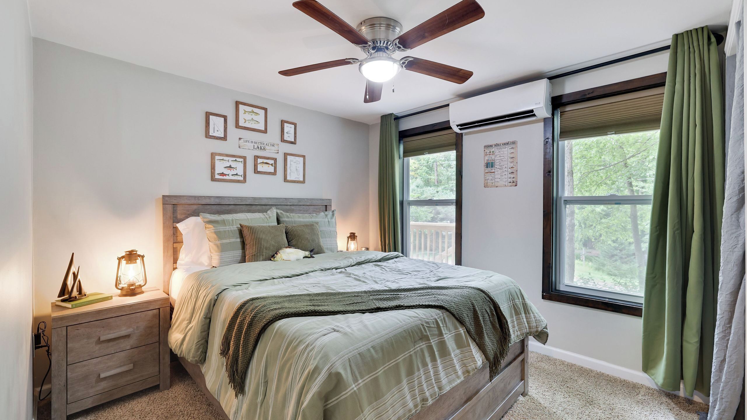 A bedroom with a bed, a nightstand, a ceiling fan, a window with curtains, and wall decorations.