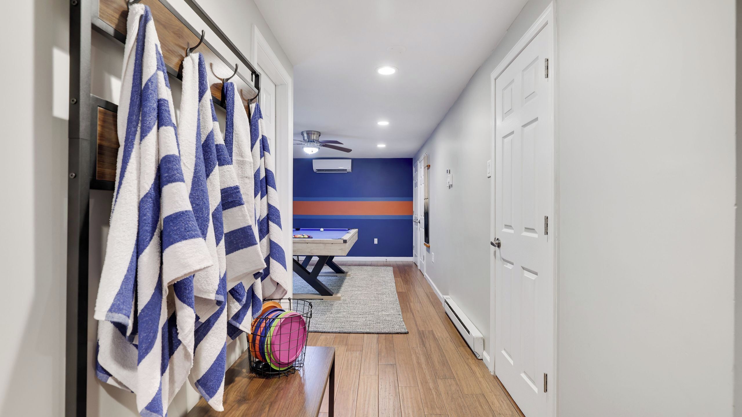 A hallway with a pool table, towels, and a ceiling fan.
