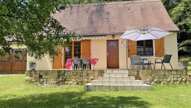 A two-story house with a stone foundation, a tiled roof, and a front porch with a table and chairs. - Charming Périgord house with above-ground pool (Mauzac-et-Grand-Castang)