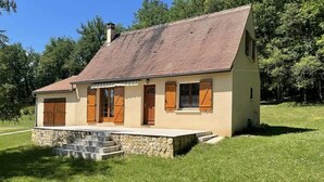 A single-story house with a sloped roof, wooden shutters, and a stone foundation. - Charming Périgord house with above-ground pool (Mauzac-et-Grand-Castang)