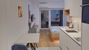 A compact studio apartment with a kitchenette, a dining area, and a bedroom.