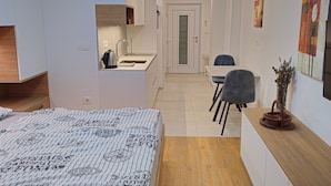 A compact room with a bed, kitchenette, and a small dining area.
