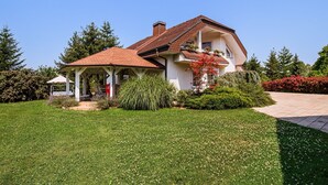 A two-story house with a red-tiled roof, a covered porch, and a well-maintained garden. - Stunning Rural Holiday Home with Garden and BBQ - Four Bedroom Holiday Home (Brežice)