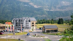 A modern building with a unique architectural design, situated in a mountainous area with a road in the foreground.