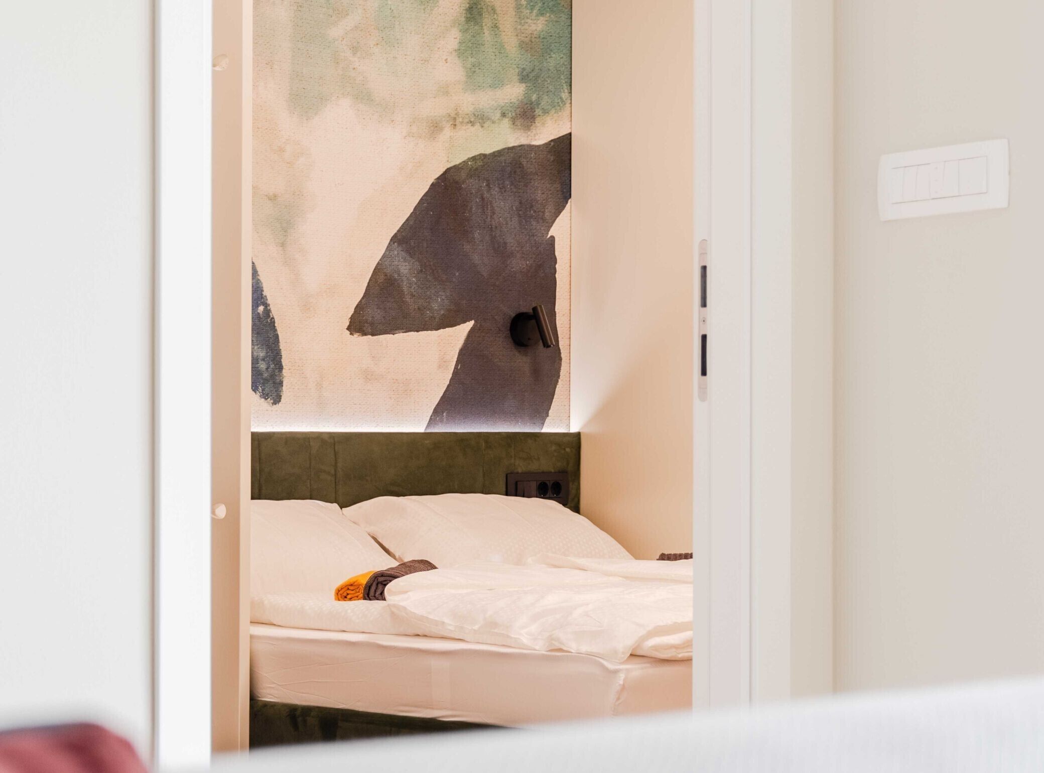 Ein Hotelzimmer mit einem Bett, einem Kopfteil und einer Wand mit einem teilweisen Blick auf ein Gemälde.