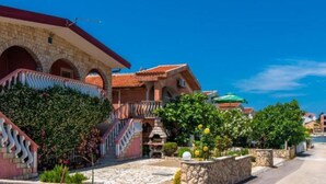 A coastal building with a stone facade, red-tiled roof, and a staircase leading to a balcony. - Leček Cozy Apartments - Two Bedroom 3 (Vir)