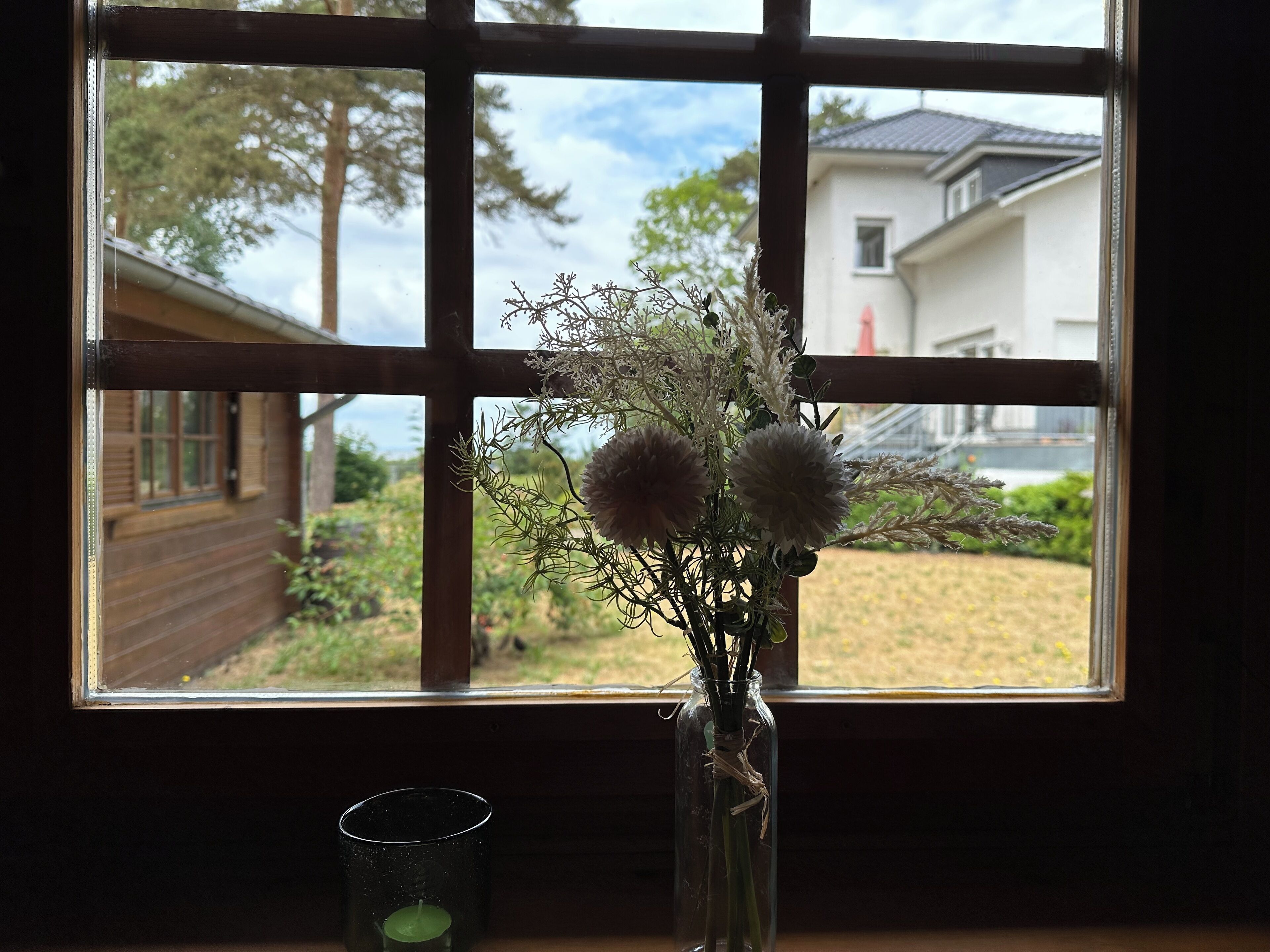 Ein Fenster mit Blick auf ein Haus und einen Garten.