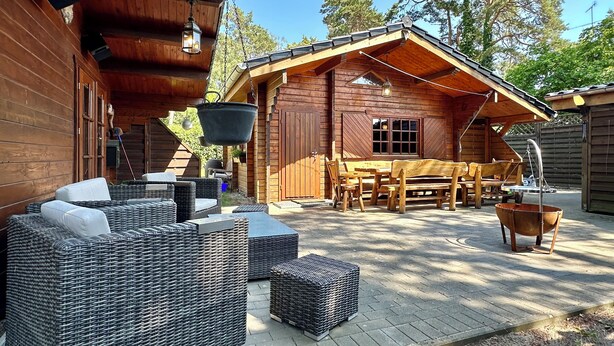 A wooden cabin with wicker furniture and a hanging light fixture. - Almhuetten-am-Meer.de (Lubmin)