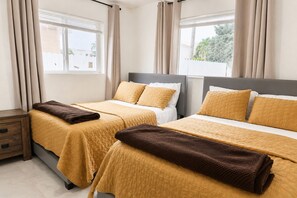 A hotel room with two beds, beige curtains, and a view of the outside. - Miami 2BR Home • Jackson Hospital - Parking (Miami)