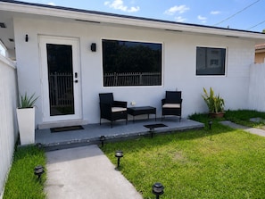 A single-story house with a front porch, two chairs, a small table, and a potted plant. - Miami 2BR Home • Jackson Hospital - Parking (Miami)