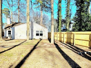 Situated in a wooded area, this single-story house features a gabled roof and a front porch.