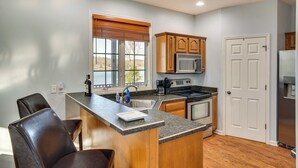 A kitchen with wooden cabinets, a granite countertop, a built-in microwave, and a stainless steel refrigerator. - Hot Tub, Dock & Views: Waterfront Home in Cadiz! (Cadiz)