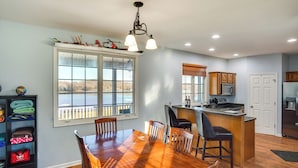 A spacious kitchen with a large island, wooden dining table, and a view of the outdoors through a large window. - Hot Tub, Dock & Views: Waterfront Home in Cadiz! (Cadiz)