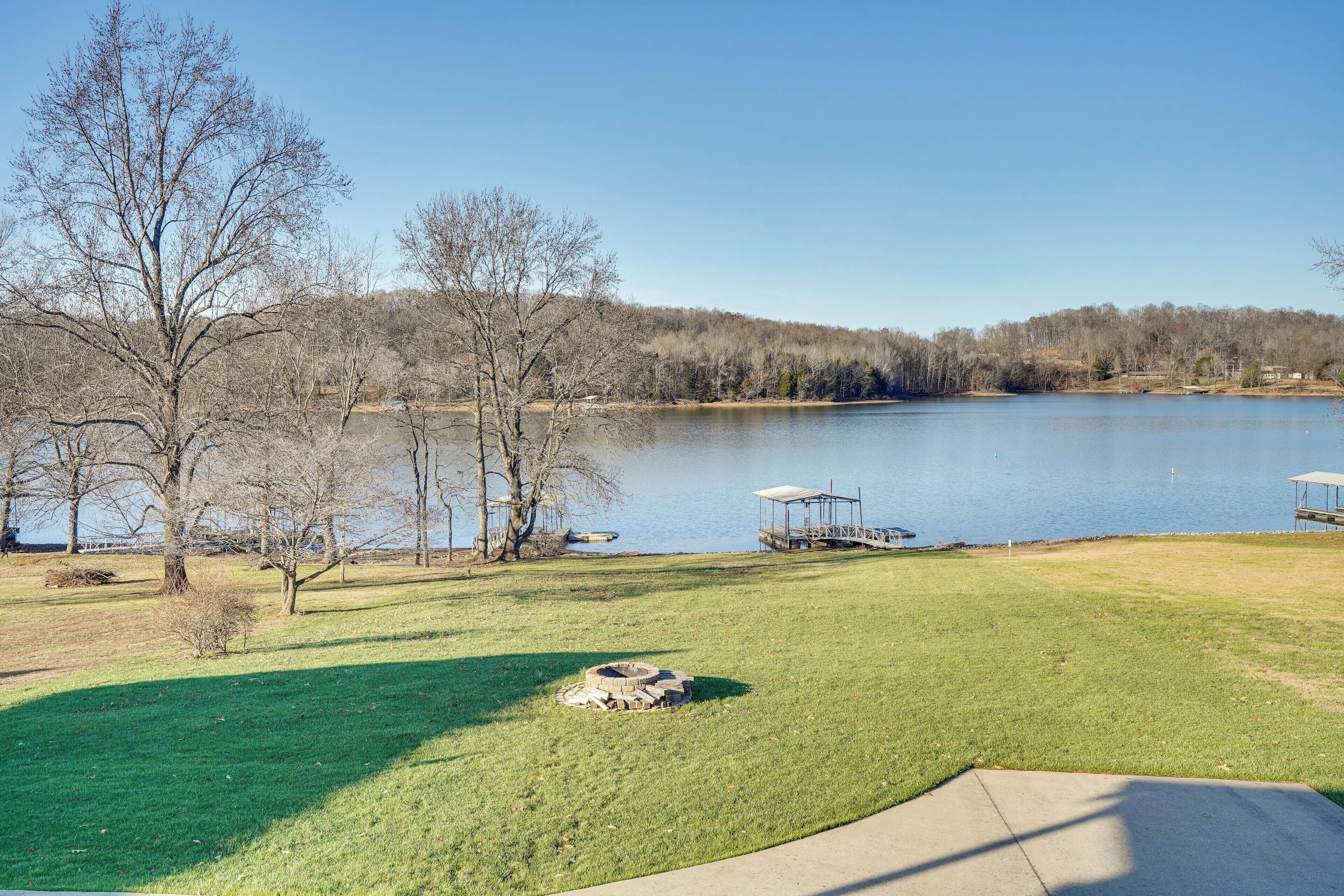 A lakeside view with a grassy area, trees, and a dock.