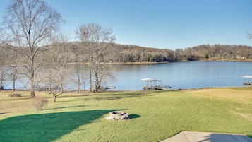 A lakeside view with a grassy area, trees, and a dock.