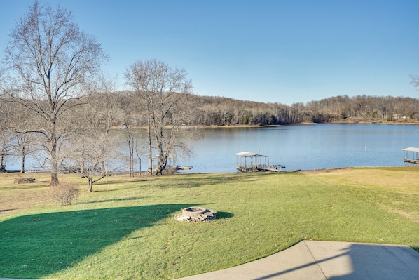 A lakeside view with a grassy area, trees, and a dock. - Hot Tub, Dock & Views: Waterfront Home in Cadiz! (Cadiz)