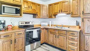 Una cocina con armarios de madera, microondas, estufa y lavamanos.