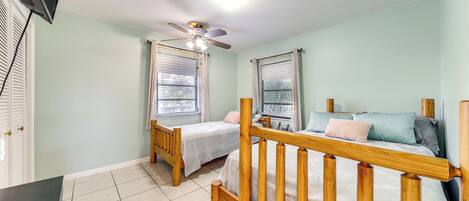 A bedroom with two single beds, a ceiling fan, and a TV.