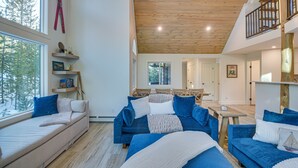 A modern living room with a wooden ceiling, a sofa, a dining table, and a staircase. - Mtn Escape w/ Hot Tub, By Trails in Grand Lake! (Grand Lake)