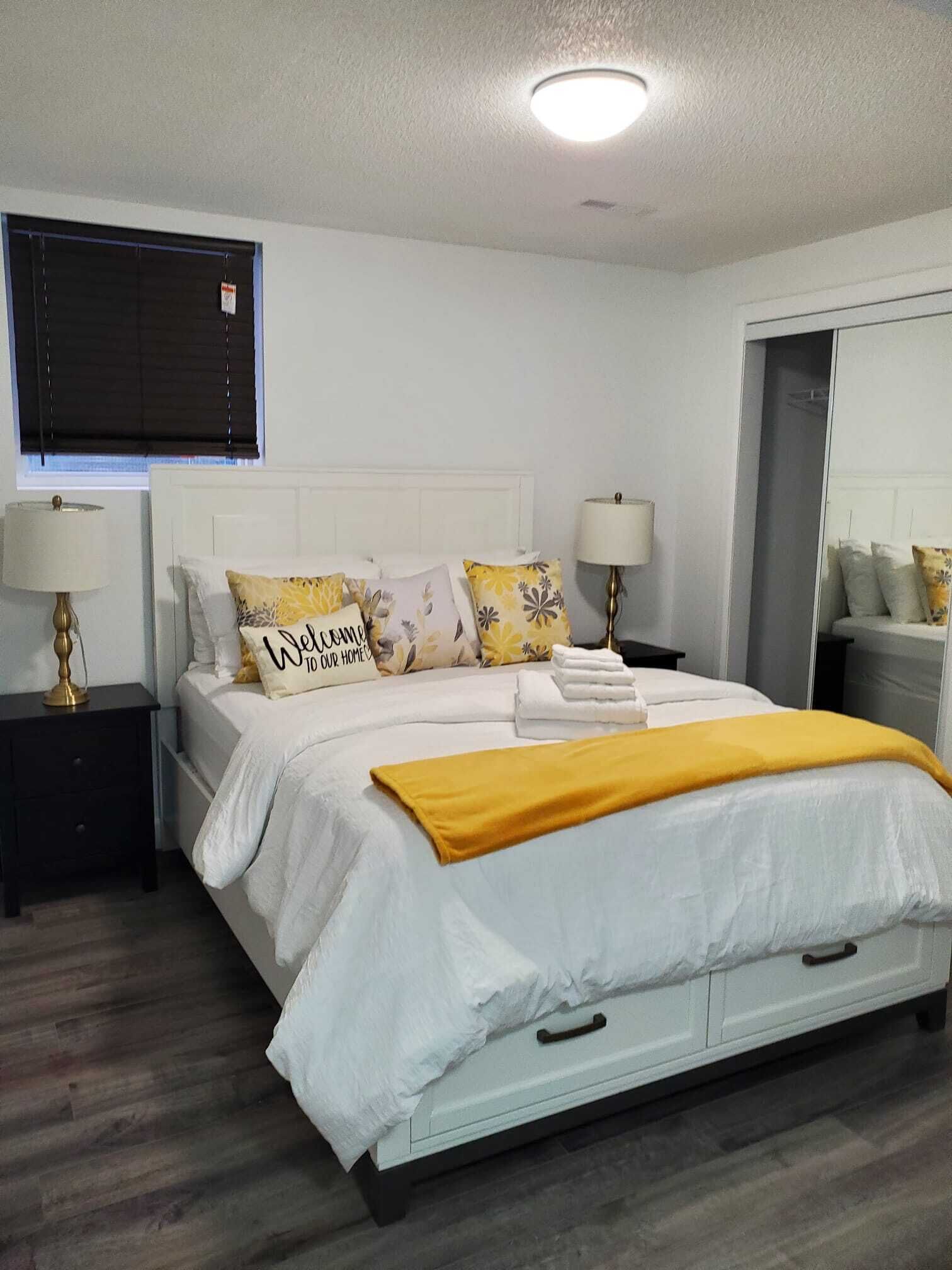 A neatly arranged bedroom with a bed, bedside tables, and a mirror.