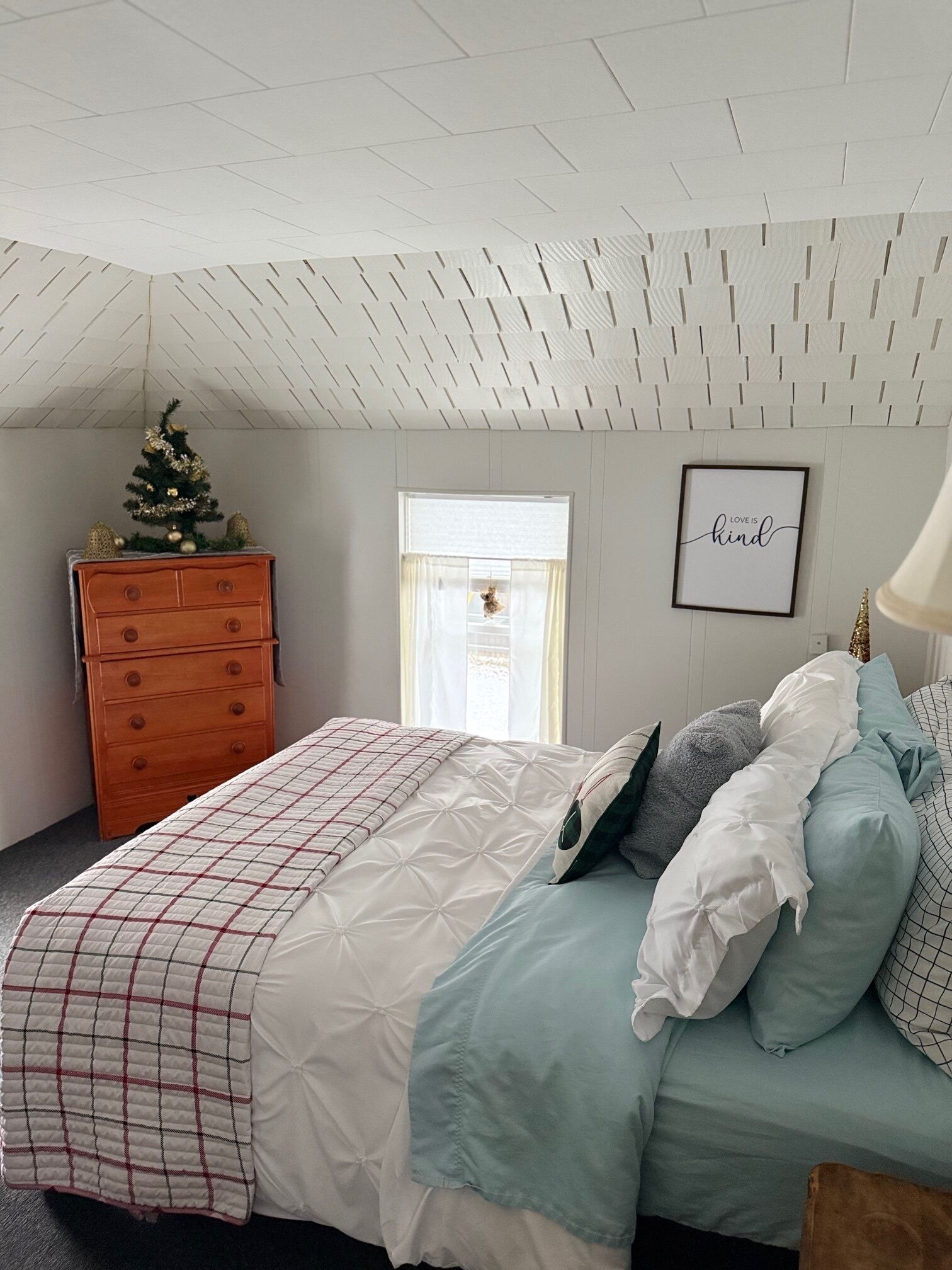 A bedroom with a bed, dresser, and a small Christmas tree.
