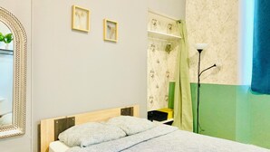 A bedroom with a bed, a wardrobe, a mirror, and a floor lamp. - T1 bis for 3 people Private and separate kitchen bathroom (Saint-Brieuc)