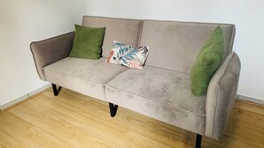 A grey sofa with black legs, two green pillows, and a colorful pillow. - T1 bis for 3 people Private and separate kitchen bathroom (Saint-Brieuc)