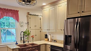 A kitchen with wooden flooring, a stainless steel refrigerator, and a window with a view of a house. - The Serene Farm Life...without all the work!  Lots of space and privacy! (Buchanan)