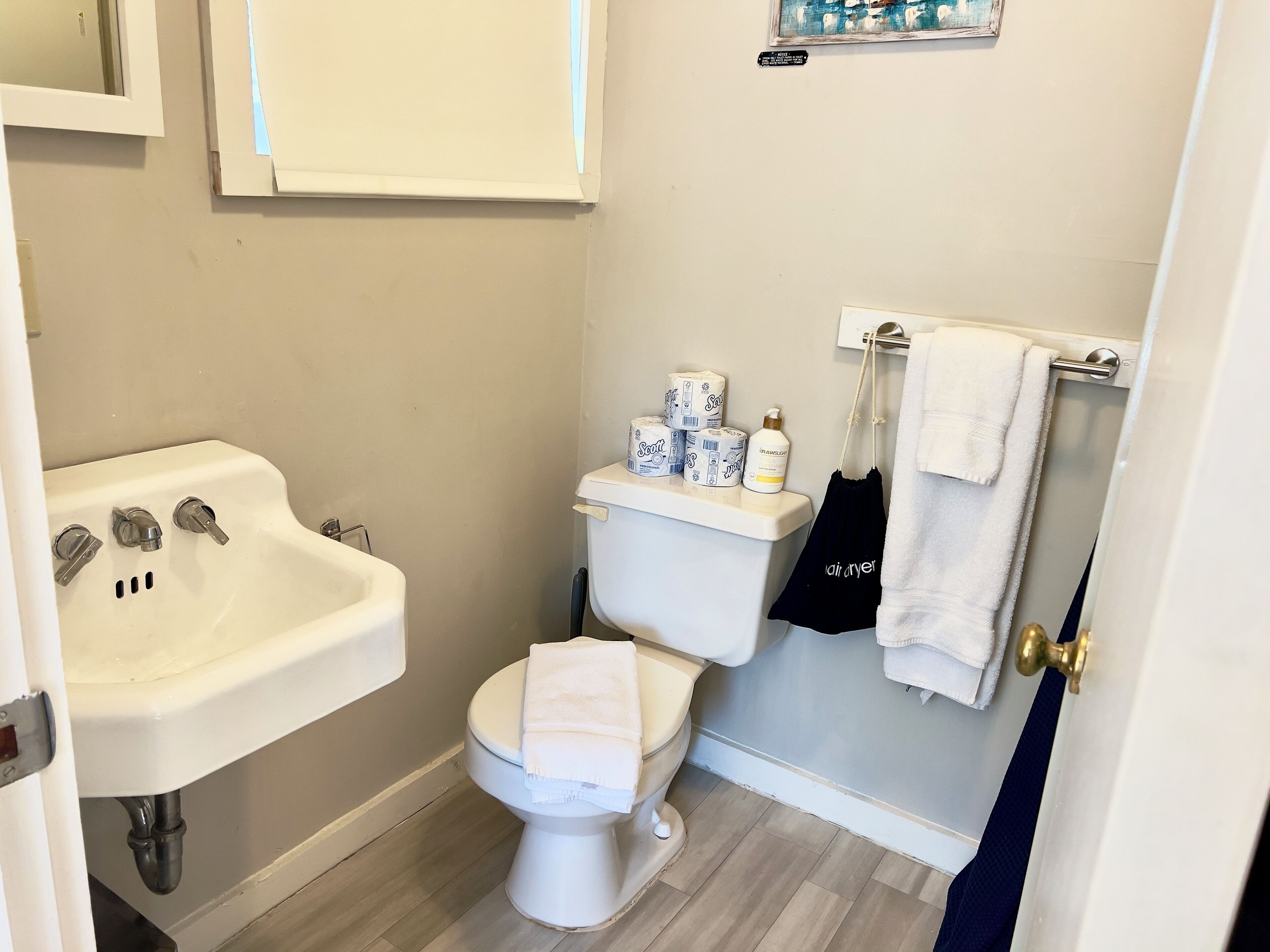 A bathroom with a white sink, toilet, and a towel rack with towels.