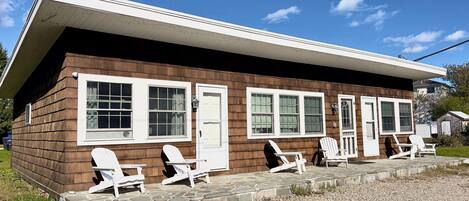 A wooden cabin with a porch, white-framed windows, and a door.