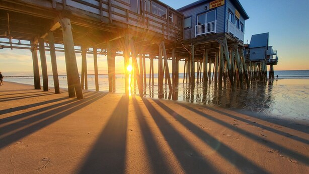 A pier with a building on stilts over the beach. - Relax and unwind in our 4 bedroom beach condo. (Old Orchard Beach)