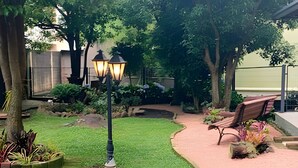 A landscaped garden with a pathway, a bench, and a street lamp. - Siga Gramado-Casa de Vó c TVsmart e Wifi (Gramado)