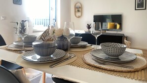 A dining area with a table set for four, featuring patterned bowls and wine glasses. - Luxurious 2-room apartment, WLAN, washing machine (Schönefeld)