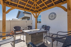 An outdoor patio with wicker furniture, a fire feature, and a compass wall decoration. - Junction Escape: Pet Friendly + Office Space (Grand Junction)