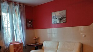 Ein Wohnzimmer mit einem beigen Sofa, einem kleinen weißen Tisch und einer roten Wand mit einem Gemälde.