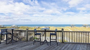 A wooden deck with outdoor seating and a view of the beach. - Sleeps 28 Beachfront w/ Pool, Hot Tub, Game Room Atlantic Watch by Avantstay (Kill Devil Hills)