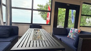 A room with a table, two sofas, and large windows with a view of trees and a flag.